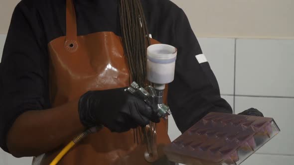 Cheerful Female Chef Using Airbrush Decorating Chocolate Mold alt