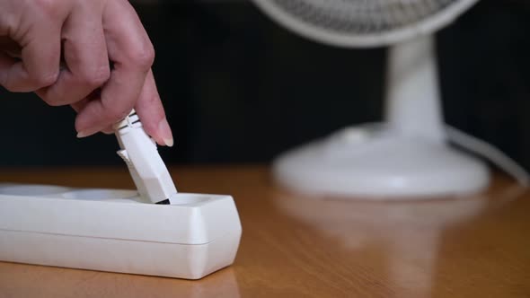 the woman plugs in the plug and turns on the household fan. woman with fan. alt