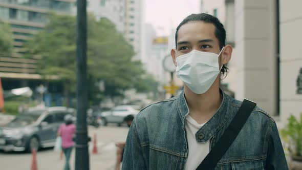 Handsome man wearing a surgical mask while walking on the street in the city.