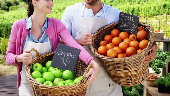 Happy couple holding basket full of fresh fruits alt