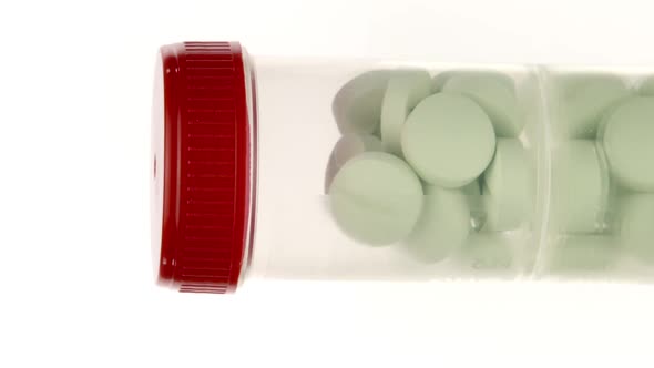 Vertical Video Transparent Pills Bottle with Large Green Pills Isolated on White 360 Rotating