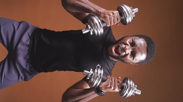A Closeup of an AfricanAmerican Man Lifting Dumbbells Demonstrates a Winning Gesture