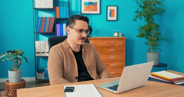 Video Call Via Webcam in Company Office Man with Glasses Sits Behind Desk in Front alt