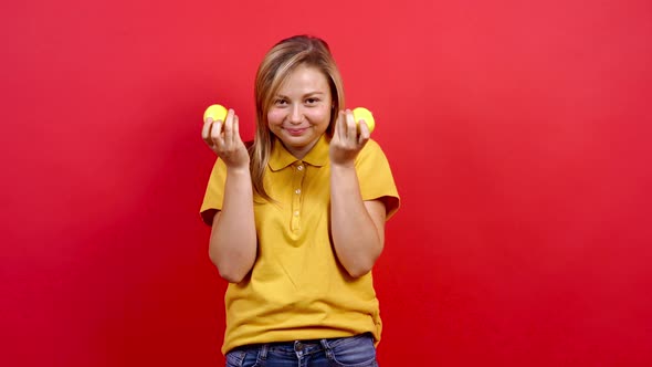 Cute and Slightly Fat Girl in a Yellow T-shirt Plays and Smells Two Lemons, alt