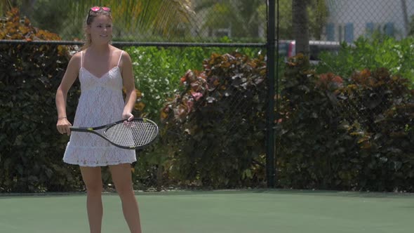 A young woman playing tennis with her boyfriend while on vacation. alt