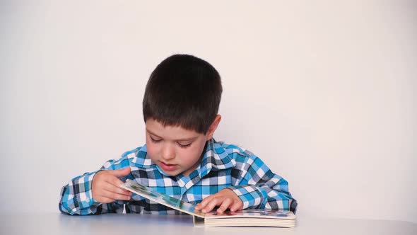 A Preschool Boy Reads a Book Closes It and Pushes It Away From Himself alt