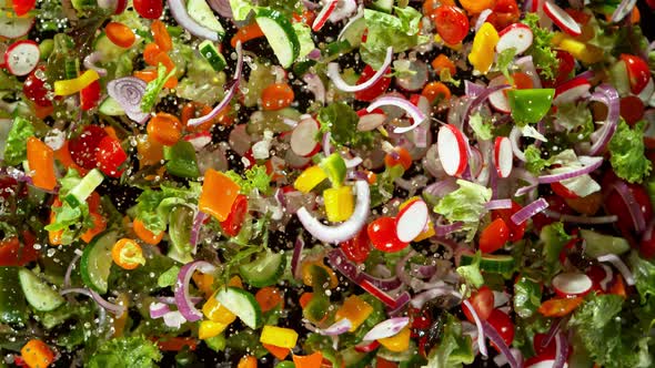 Super Slow Motion Shot of Flying Cuts of Colorful Fresh Vegetables and Water Drops at 1000Fps alt