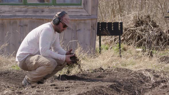 Man checks the soil on a farm, agriculture, wide shot slow motion alt