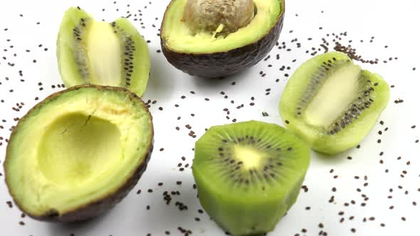 Fruits and seeds of avocado and kiwi lie on a white table.