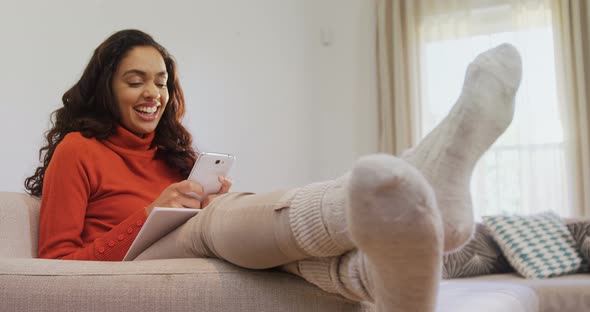 Woman sitting on sofa laughing while using her mobile phone 4K 4k alt