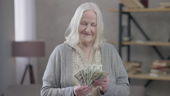 Wealthy Old Caucasian Woman Holding Cash Dollars As Fan Looking at Camera Smiling alt
