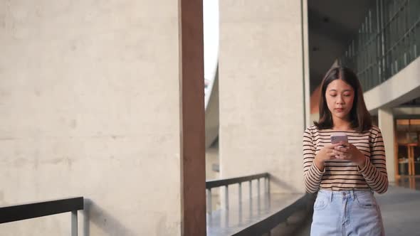 A woman succeeds using a smartphone while walking down the street in front of a  alt