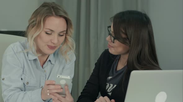 Two Office Girls Laughing and Having Fun Looking at the Phone alt