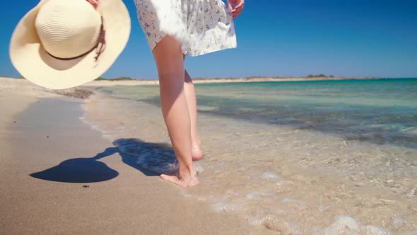 Barefoot Woman Walks Along Sea Coast Beach with Hat