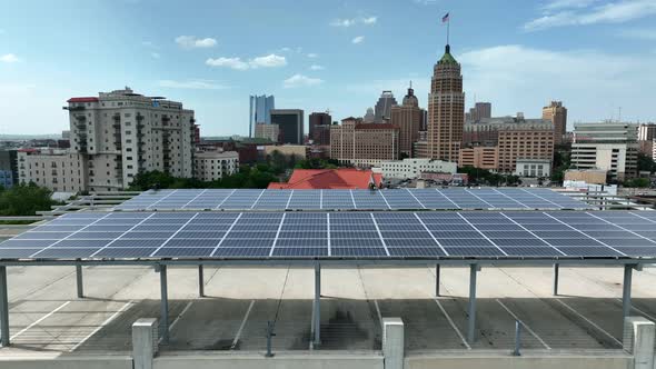 Solar panel array with urban American city skyline in distance. Aerial truck shot. alt