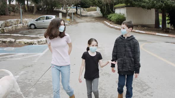 Coronavirus pandemic - kids walking outdoors with face masks to avoid corona alt