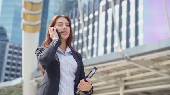 Asian young smart business woman talking in telephone call in city while walk to office workplace. alt