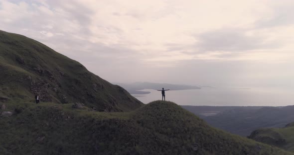 Drone fotoage of a man who rises his hands after reaching the top of Cerro Chame mountain, district alt