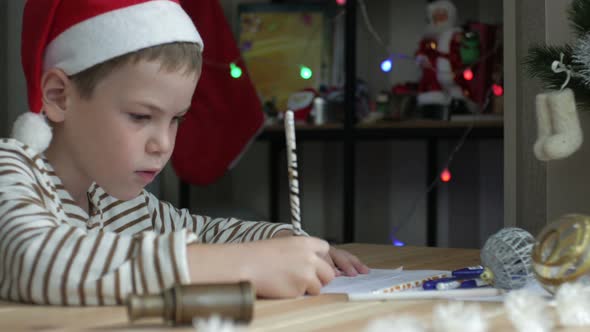 kid in a Christmas hat writing a letter to Santa Claus