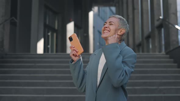 Woman Gesturing Happily While Getting Good News on Mobile alt