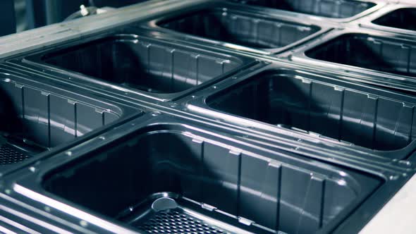 Closeup of Black Plastic Containers Molding Process alt