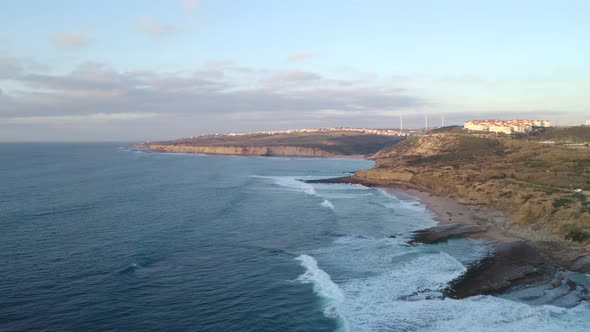 Ericeira drone aerial view on the coast of Portugal with surfers on the sea at sunset alt