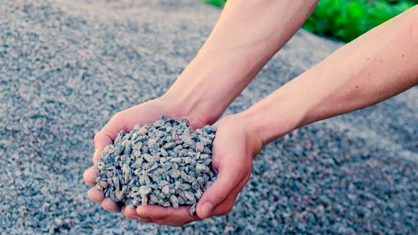 A Man Holds Small Rubble in His Hands alt