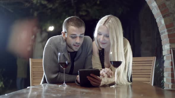 Couple in Love Smiles with Wine Uses Tablet in Rural Farm House Tuscany Italy at Night Slow Motion alt