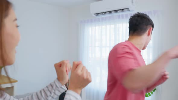 Asian young loving couple dance with music together in living room. alt