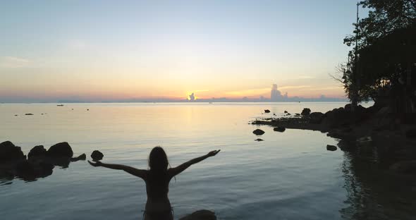 Thailand Sunset Aerial Silhouette Woman Rise Up Hands on Ocean Stony Shore
