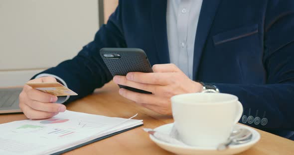 A Businessman Is Sitting at a Table in a Cafe and Working alt