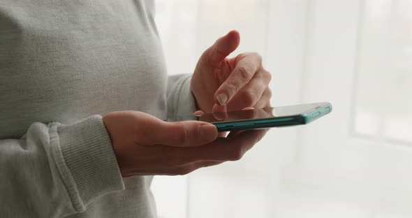 Smartphone in the cropped hands of a woman. Using a mobile phone, close-up. alt