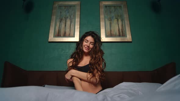 Smiling Woman Posing on Bed. Sensual Girl Playing Curls in Bedroom. alt
