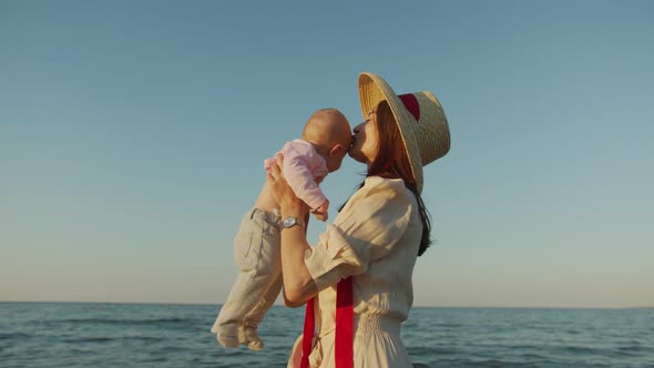 Young Mother Holding Her Baby in Front of Her at the Sea