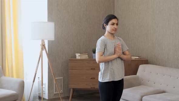 A Young Indian Woman Is Doing Yoga Meditation At Home, Standing in A Bright Room