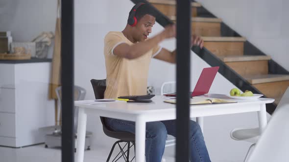 Excited African American Man Making Victory Gesture in Slow Motion Typing on Laptop Keyboard alt