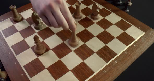 Top View of Chess Board with White Chess Pieces and Male Hand Moving Queen on Black Background alt