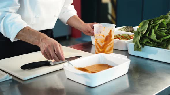 Professional restaurant kitchen, close-up: the sauce is applied to a baking sheet alt
