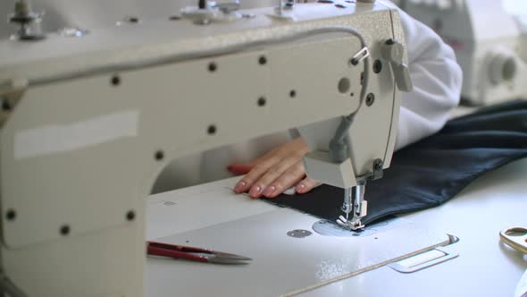 Woman Seamstress Working on a Sewing Machine in the Shop for Sewing Clothes alt