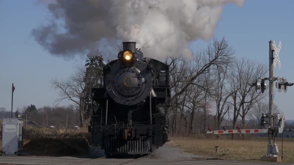 Antique restored steam engine and passenger cars approaching with smoke and steam alt