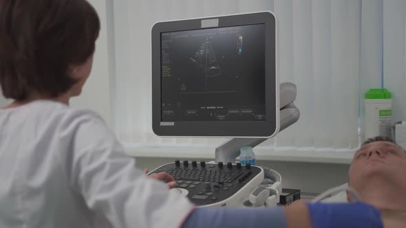 Doctor Using Ultrasound Machine to Scan Heart of a Male Patient alt