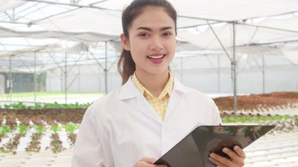Asian scientist woman looking at camera with smile hold document for research and development.