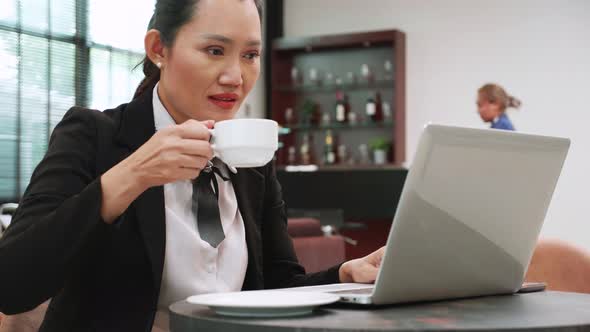 businesswoman looking laptop and drinking coffee while working on laptop, remote workplace