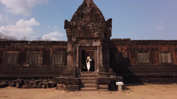 Woman in vietnamese hat go up the stairs to palace, Wat Phou Hindu Temple, ancient architecture Laos alt