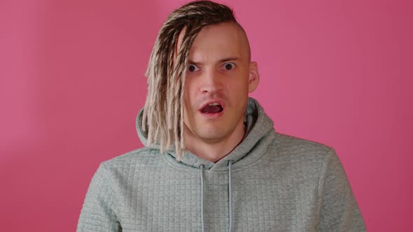 Young Handsome Shocked Man Looking at Camera with Horror on Pink Background alt