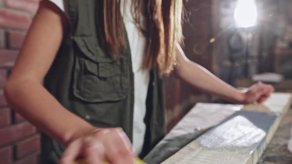 Girl Sanding Wood Beam to Smooth It Down alt