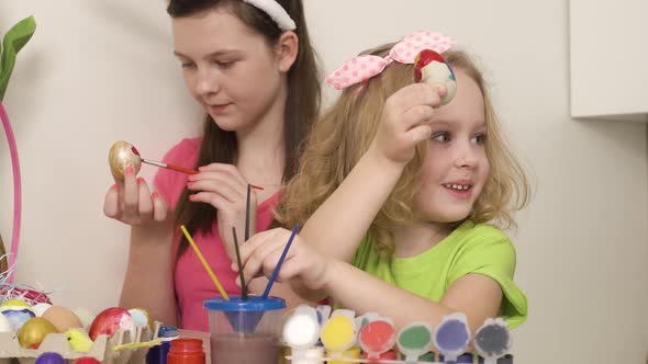 A Girl with Wavy Hair Shows Her Friends an Egg That She Painted with Paint