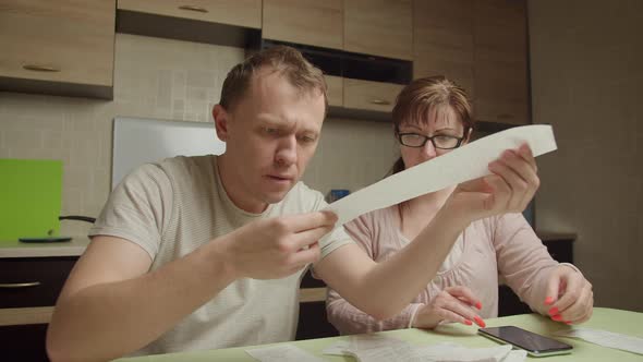 Family in the evening sitting at the table checking expenses on checks, family budget crisis