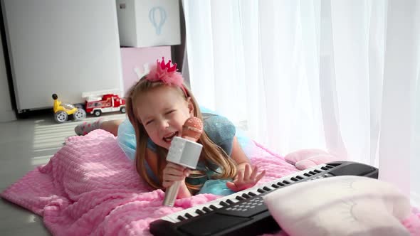 Beautiful little girl in a princess costume sings into a karaoke microphone.