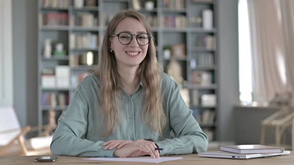 Cheerful Woman Smiling and Looking at Camera While Sitting alt